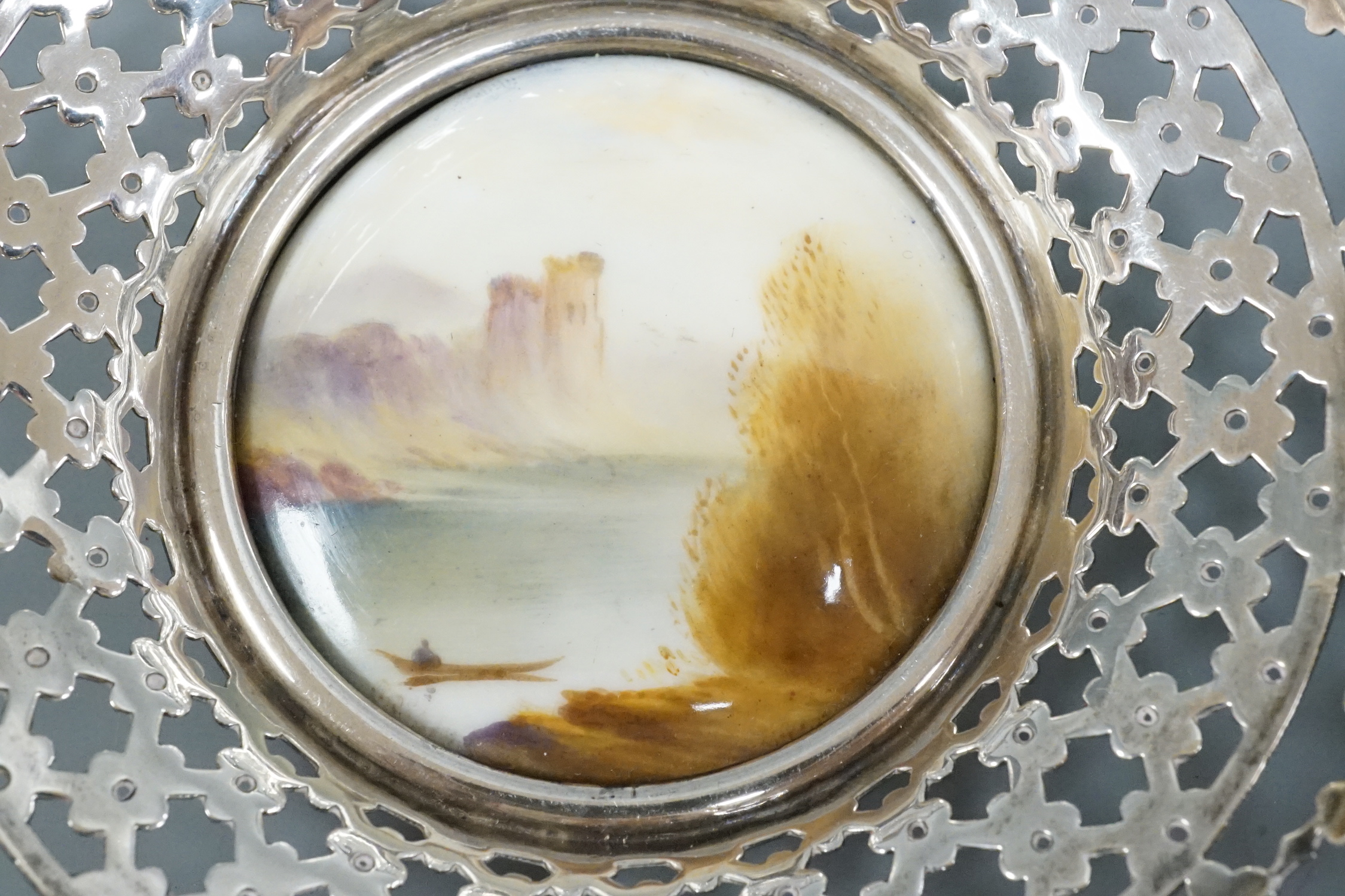 A pair of George V pierced silver mounted Royal Worcester panel bon bon dishes, painted by Raymond Rushton, hallmarked for Sanders & MacKenzie, Birmingham, 1912, diameter 10.5cm.